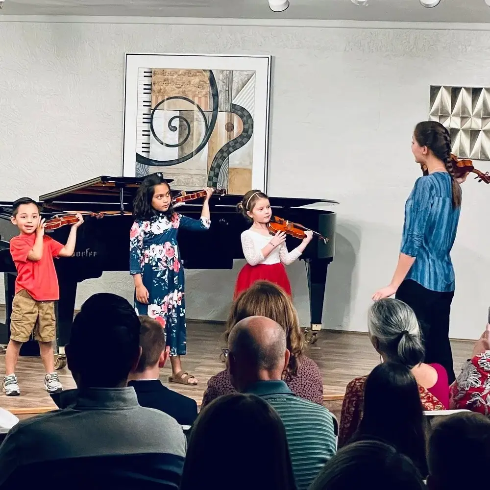 Children learning violin together in a classroom